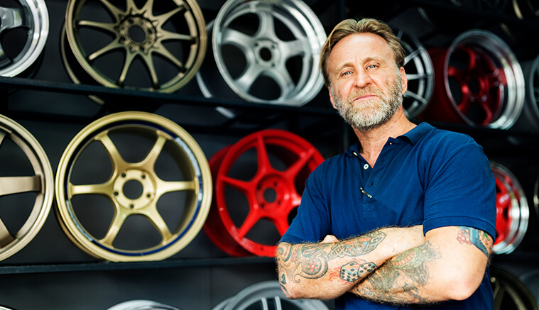 Man with tattoo sleeves standing in front of custom wheels