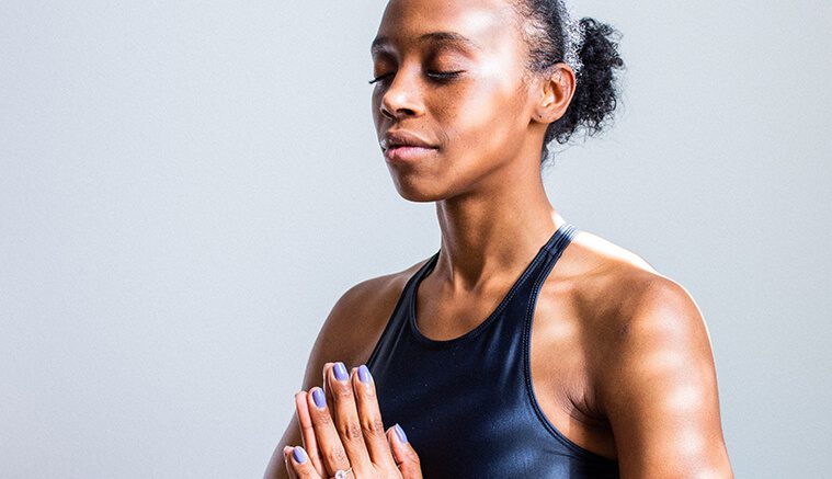 Black female in workout attire meditating to promote the importance of wellness discount program