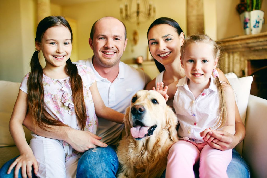 Family smiling at camera with dog